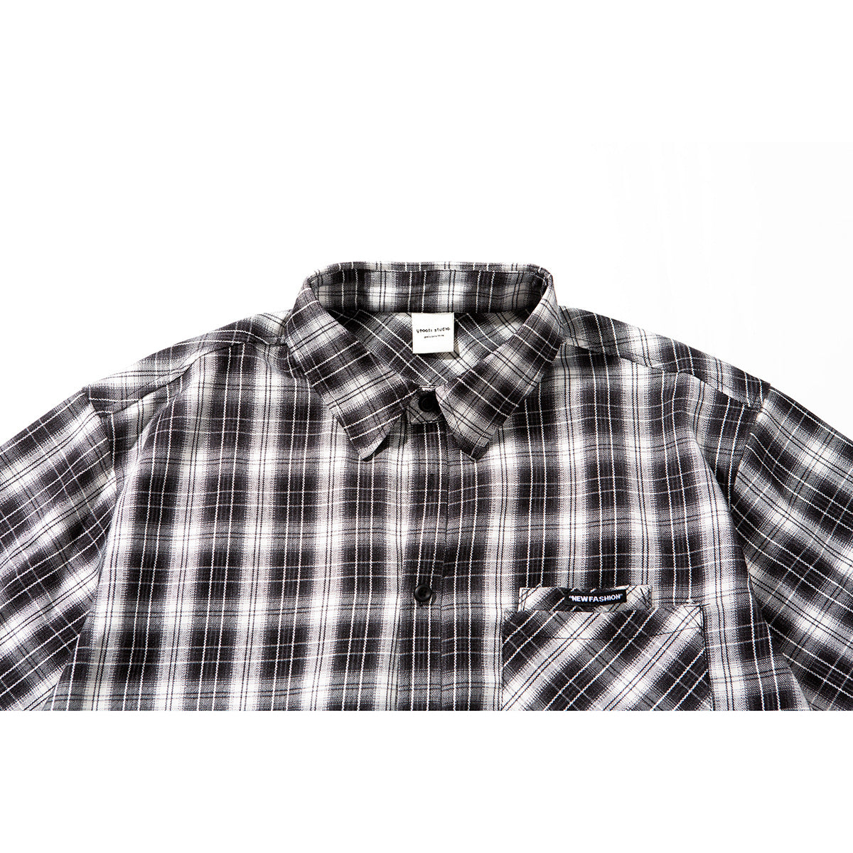 Close view of a black, gray, and white plaid button-up shirt with a pointed collar and chest pocket.