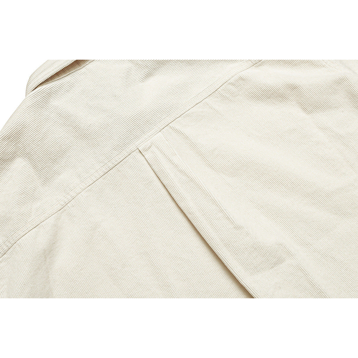 Close-up of cream ribbed shirt fabric with intersecting seams and a folded edge.