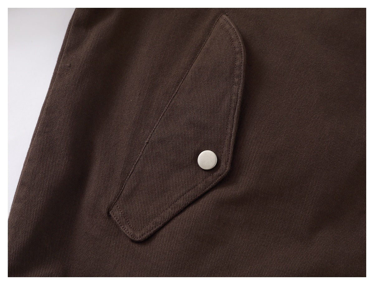 Close-up of a dark brown jacket pocket flap with a silver snap button.