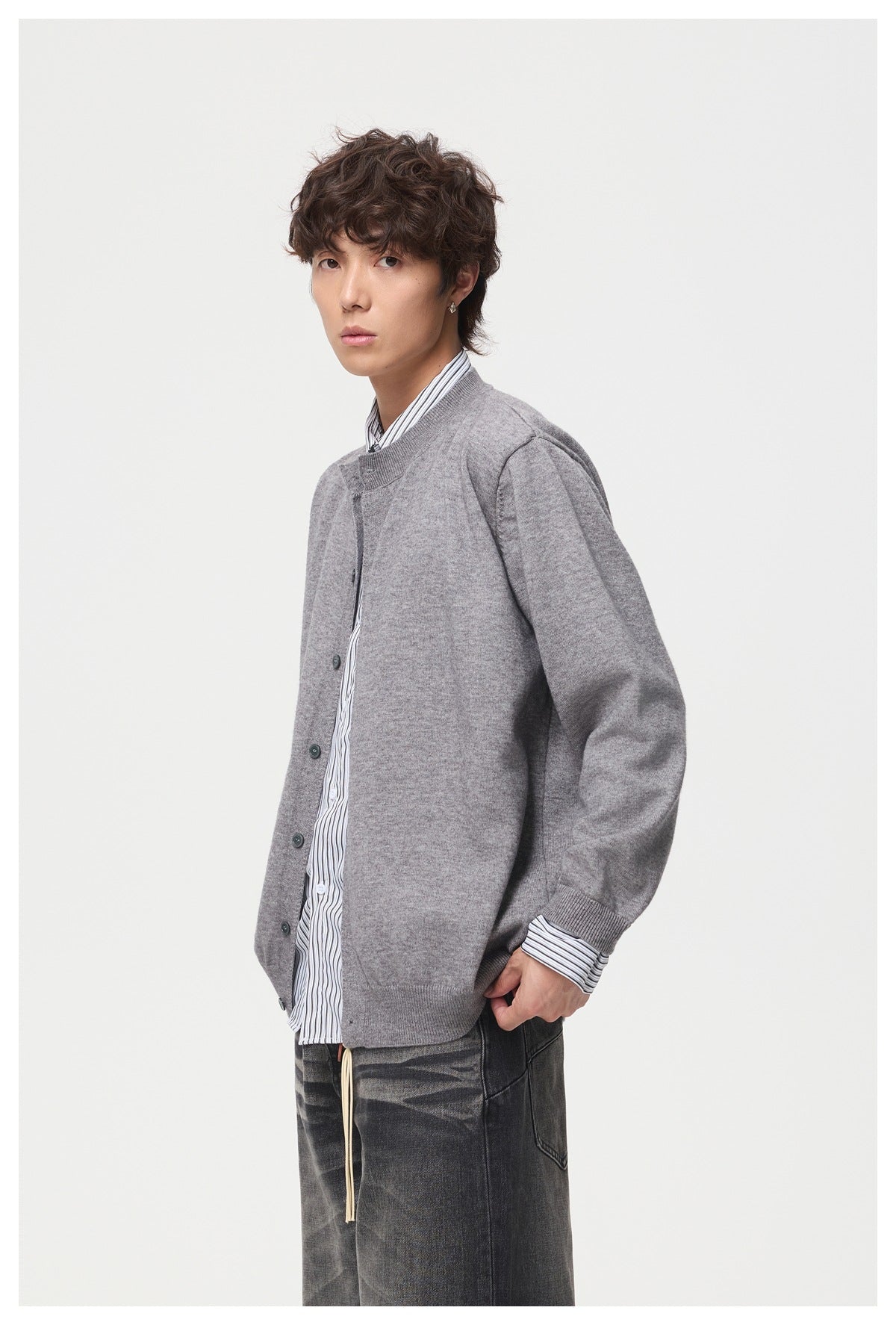 Model in a gray knit button-front cardigan with ribbed cuffs and hem over a striped shirt, three-quarter side view