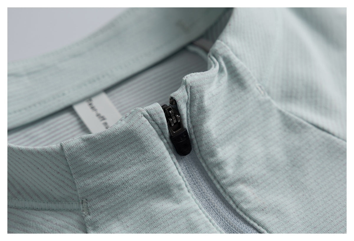Close-up of the pale gray-green collar and black zipper, with a glimpse of the striped inner neck label.