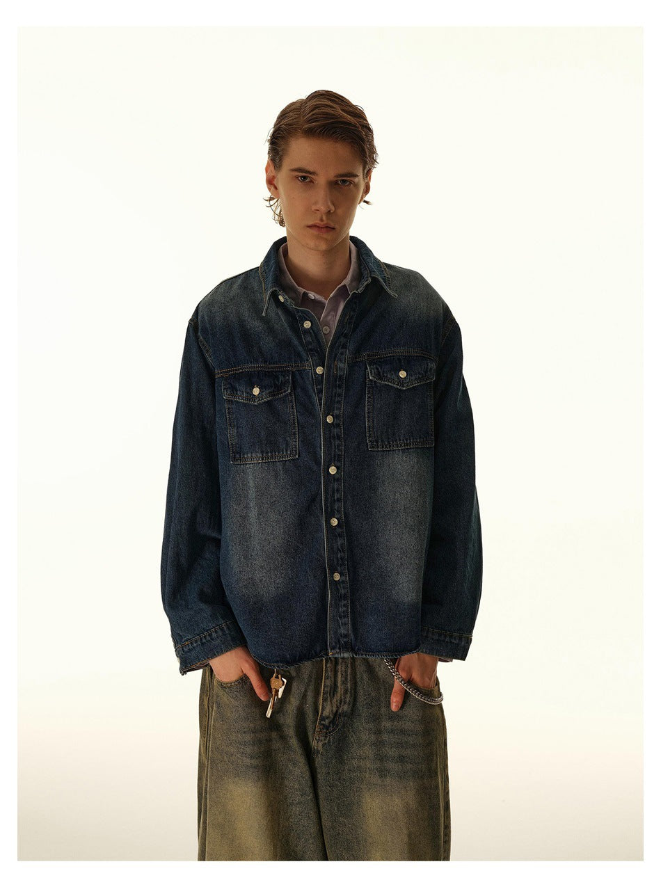 Front view of a model wearing an oversized dark indigo denim shirt with two buttoned chest pockets.