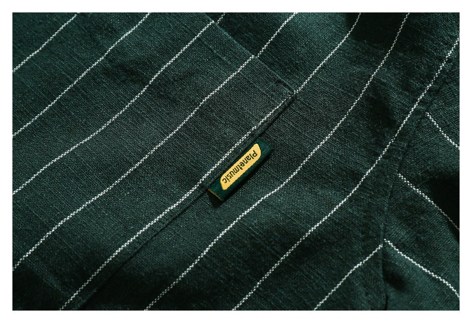 Close-up of dark green fabric with thin white stripes and a small yellow woven label.