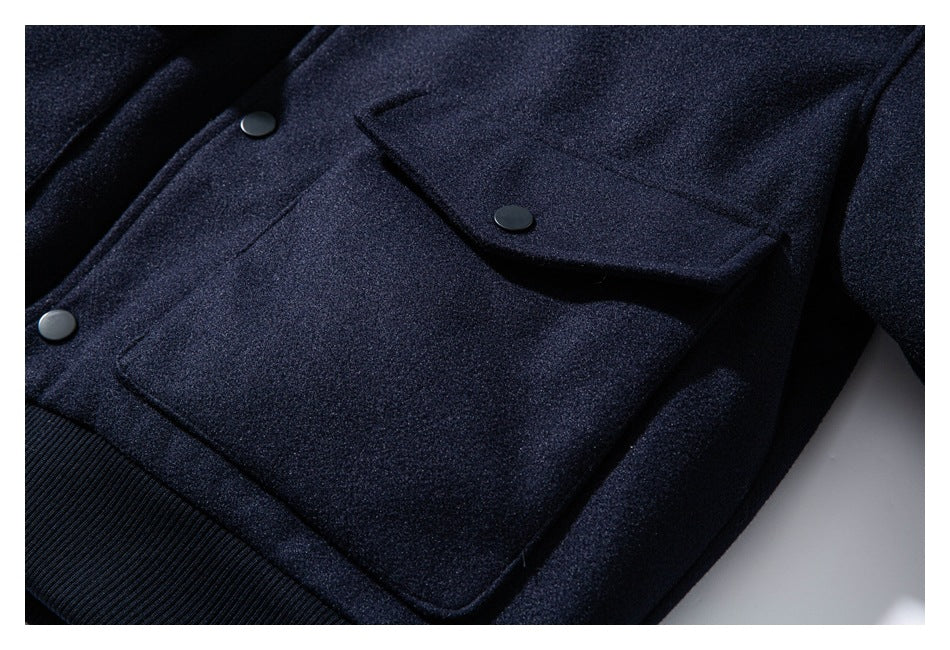 Close-up of a dark navy jacket with snap buttons, flap pockets, and a ribbed waistband.