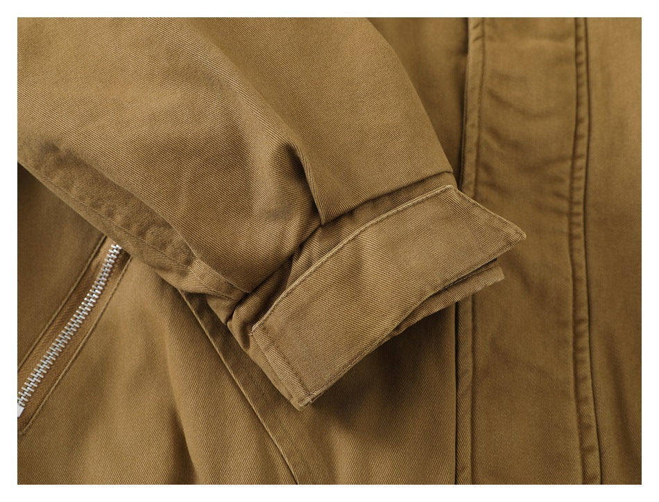 Close-up of a tan jacket sleeve with a wide cuff and a partially visible zip pocket.