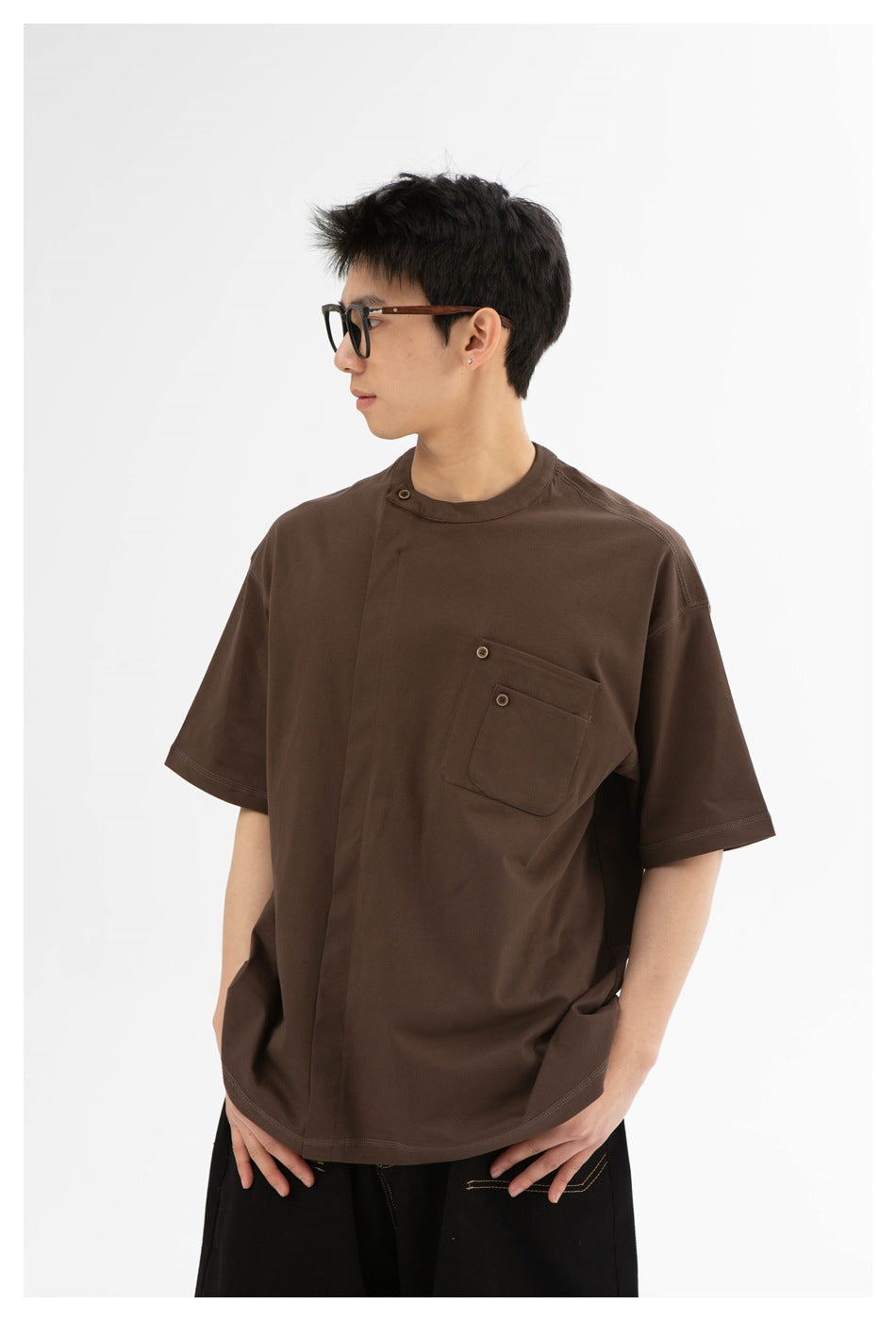 Closer view of a model wearing a dark brown oversized T-shirt with a button-detailed chest pocket.
