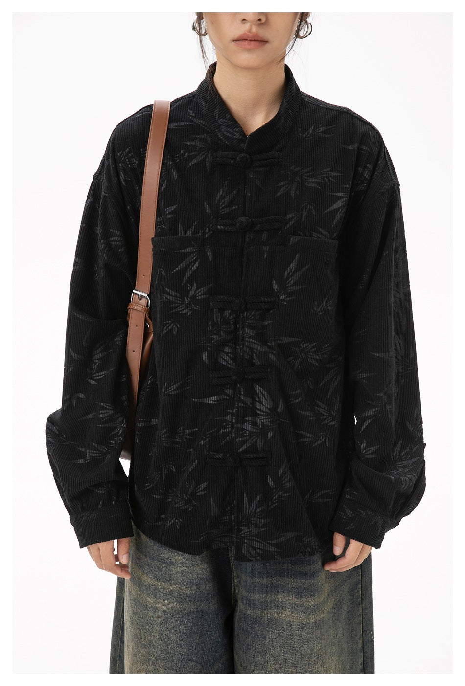 Close view of a model wearing a black bamboo-patterned jacket with frog closures and a chest pocket.