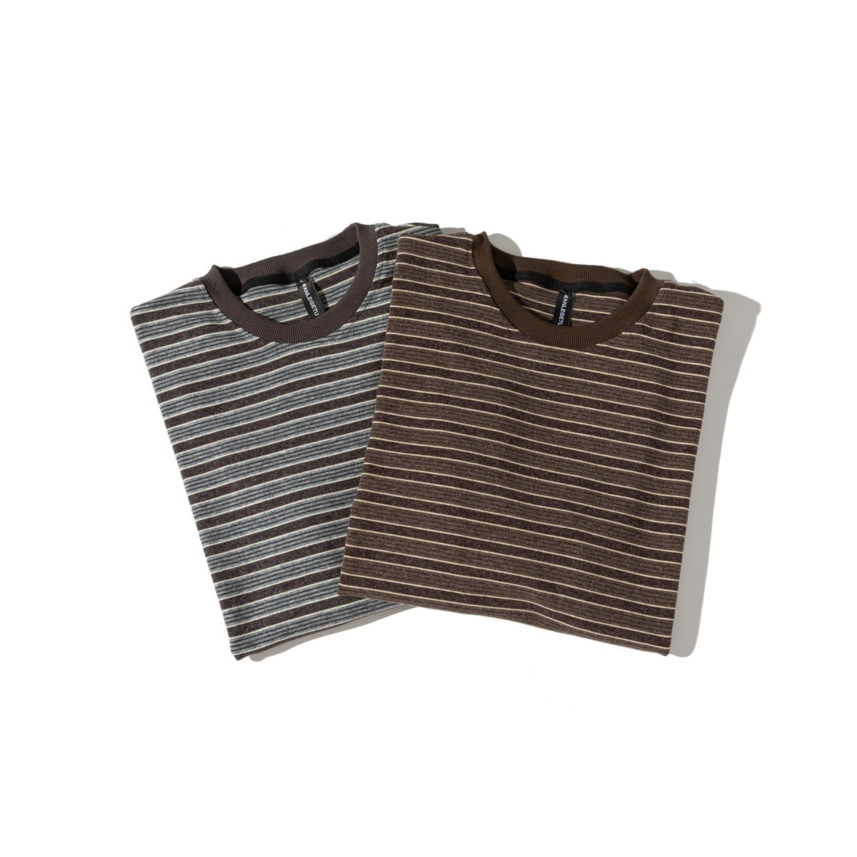Two folded striped T-shirts, gray stripe and brown stripe, with ribbed crew collars laid on a light background