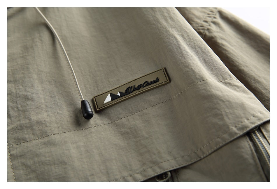 Close-up of the jacket’s sewn brand patch, drawcord end and stitched fabric.