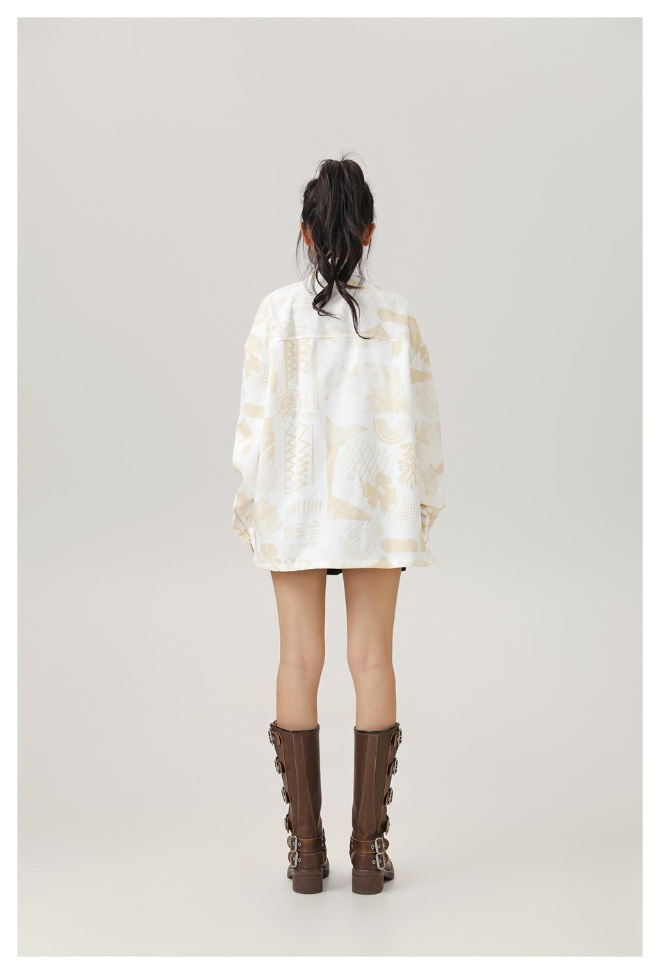 Back view of a model wearing an oversized cream shirt jacket with pale beige geometric and abstract print.