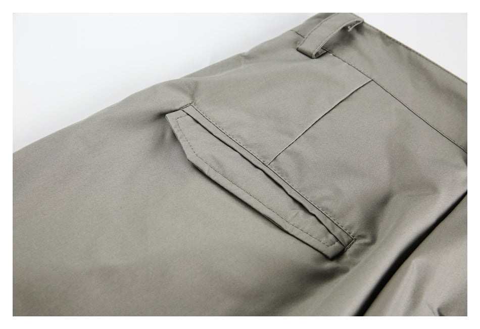 Close-up of a welt pocket and belt loop on taupe-gray trousers.