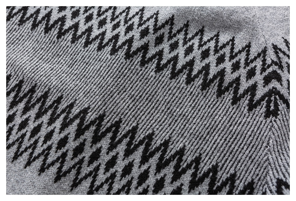 Close-up of gray knit fabric with bold black zigzag and houndstooth-like bands.
