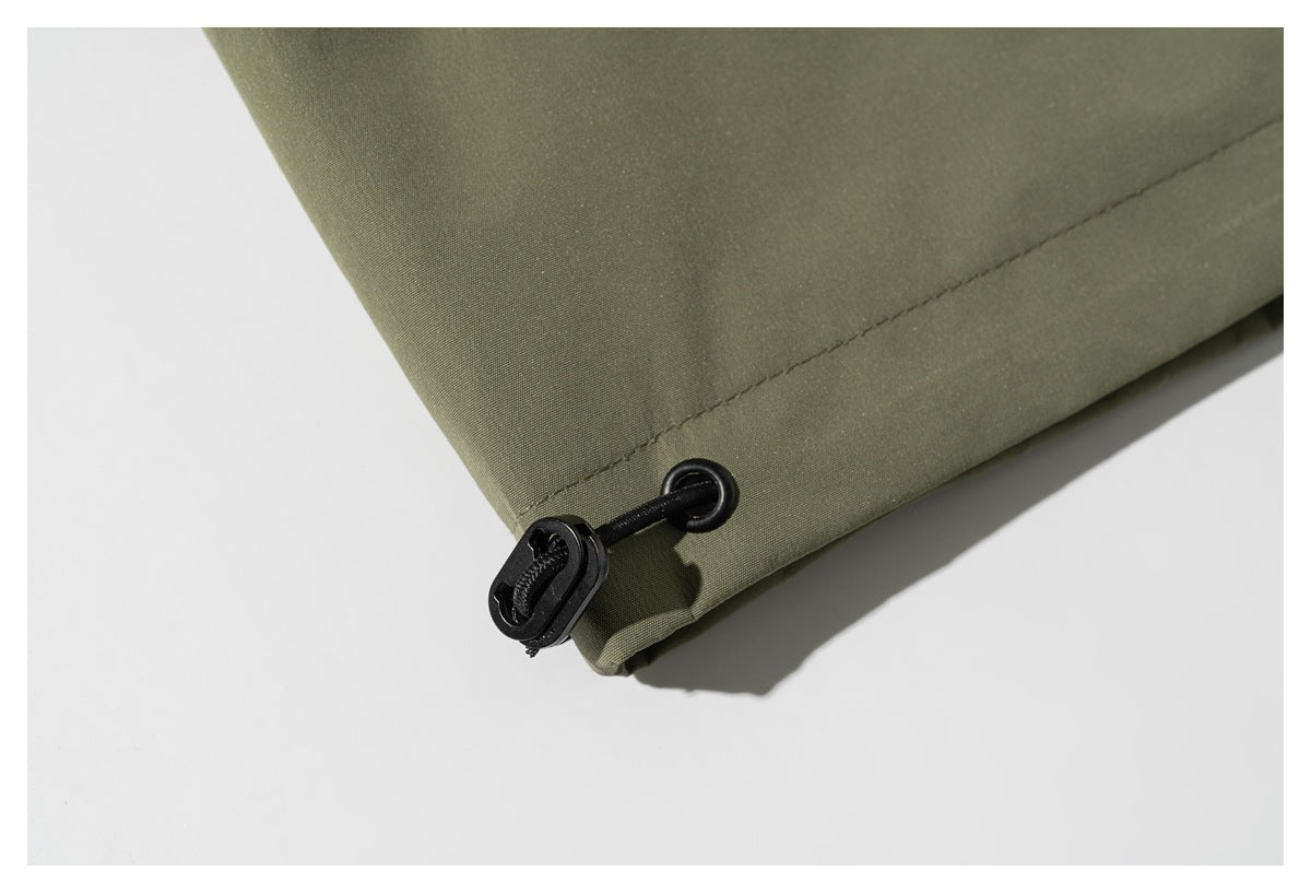 Close-up of an olive jacket hem with a black adjustable drawcord and toggle.