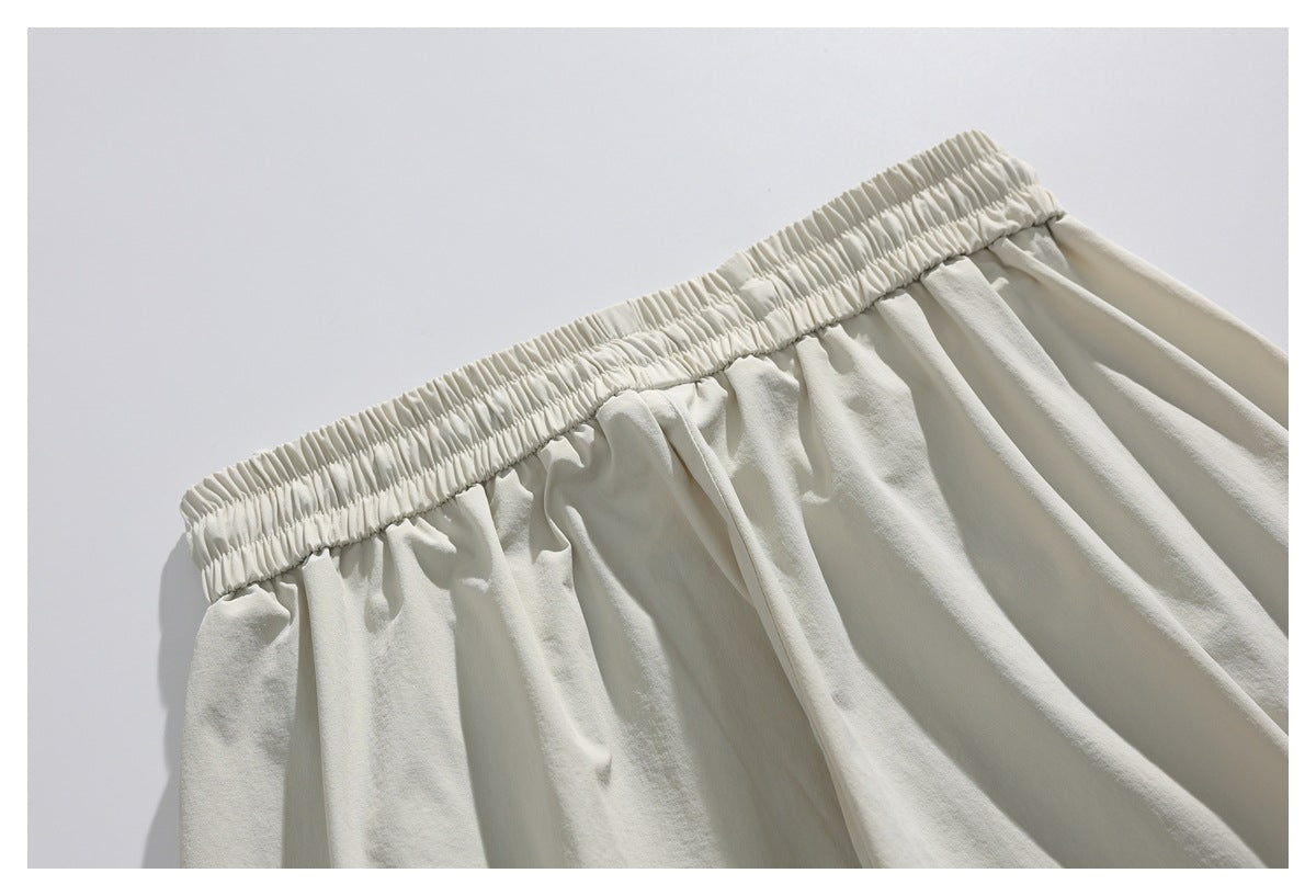 Close-up of the shorts' gathered elastic waistband and soft pleats in light ivory fabric.
