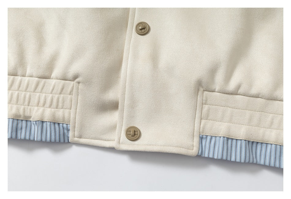 Lower front of a cream garment with tan buttons, welt pockets, and blue striped lining at the hem.