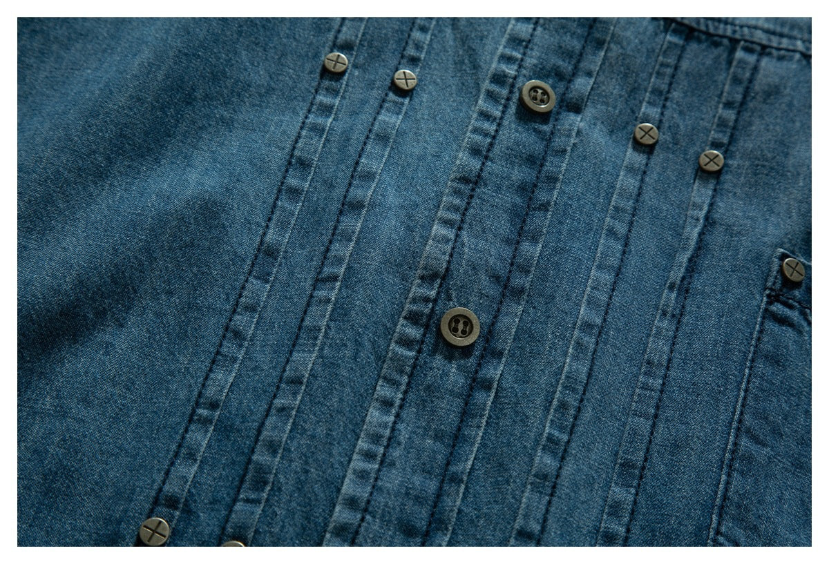 Close-up of a blue denim shirt front with vertical seams and contrasting buttons.