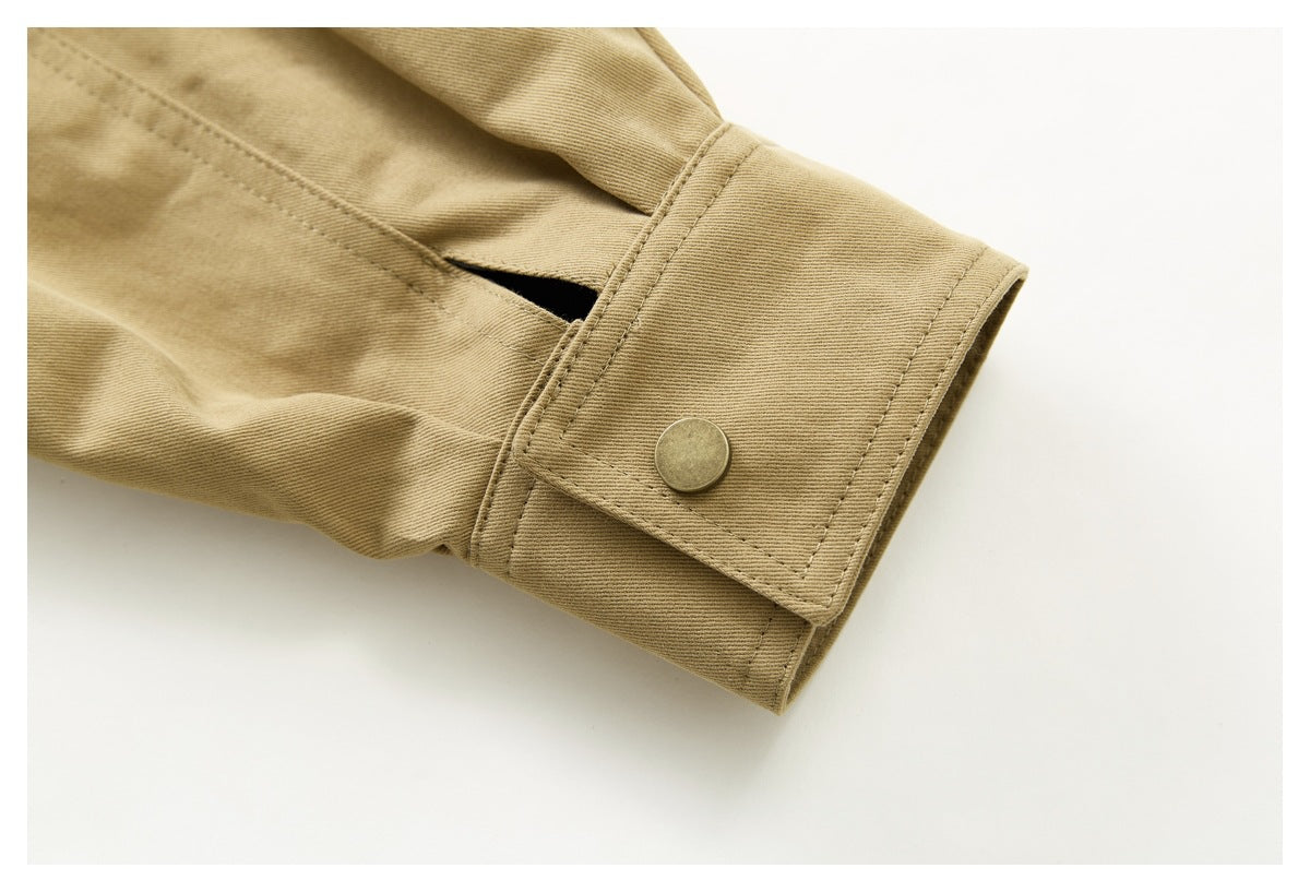 Close-up of a tan jacket sleeve cuff with a snap button and small opening.