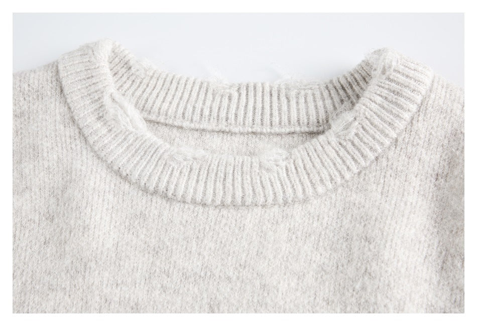 Close-up of a light gray sweater's ribbed crew neckline and fuzzy knit surface.