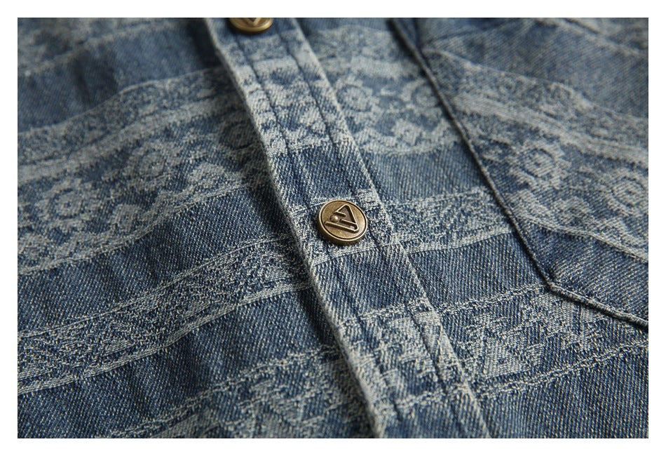 Close-up of a brass-tone button on the shirt placket against its blue geometric pattern.