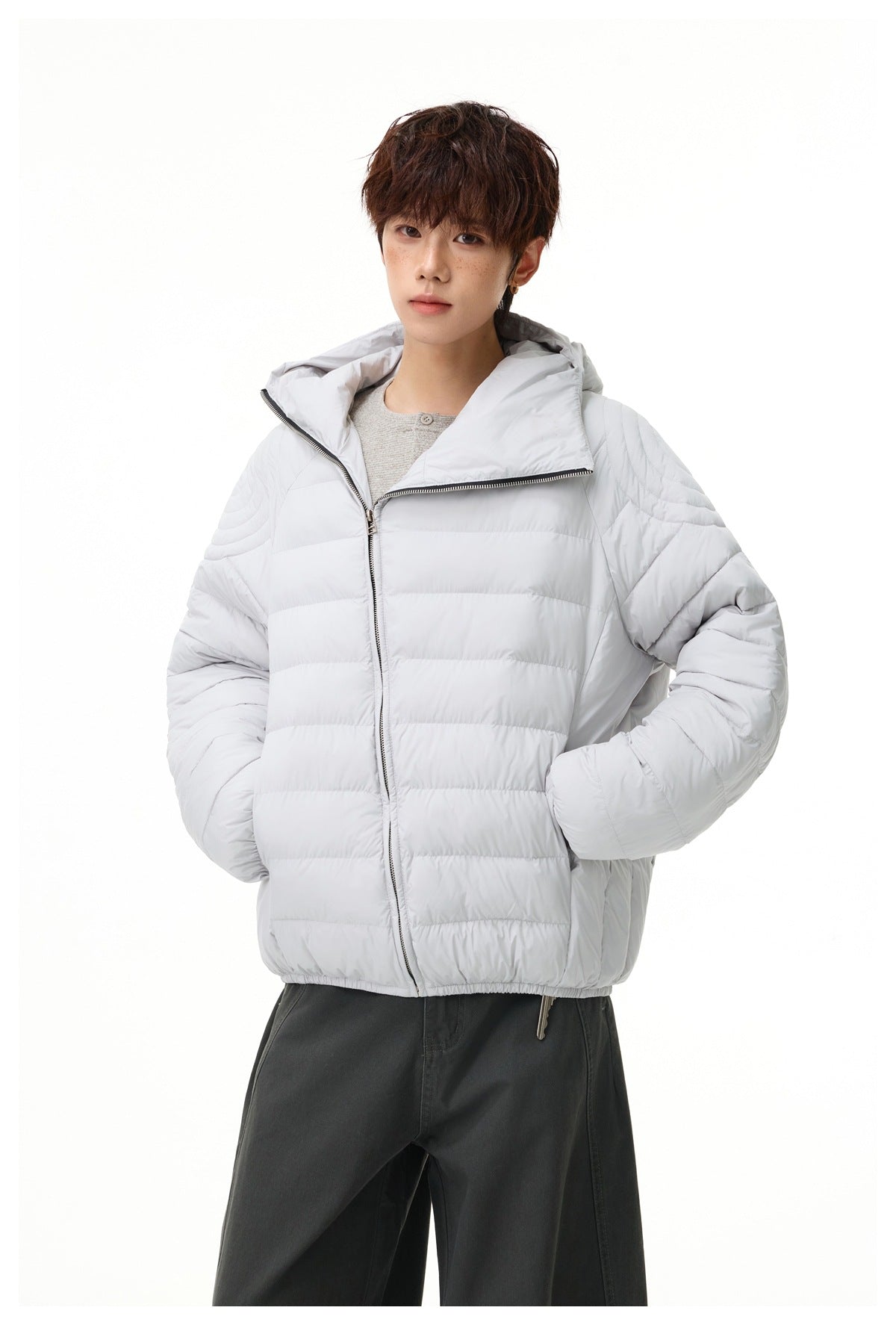 Model wearing a light gray quilted zip-front jacket with a wide open hood and collar.