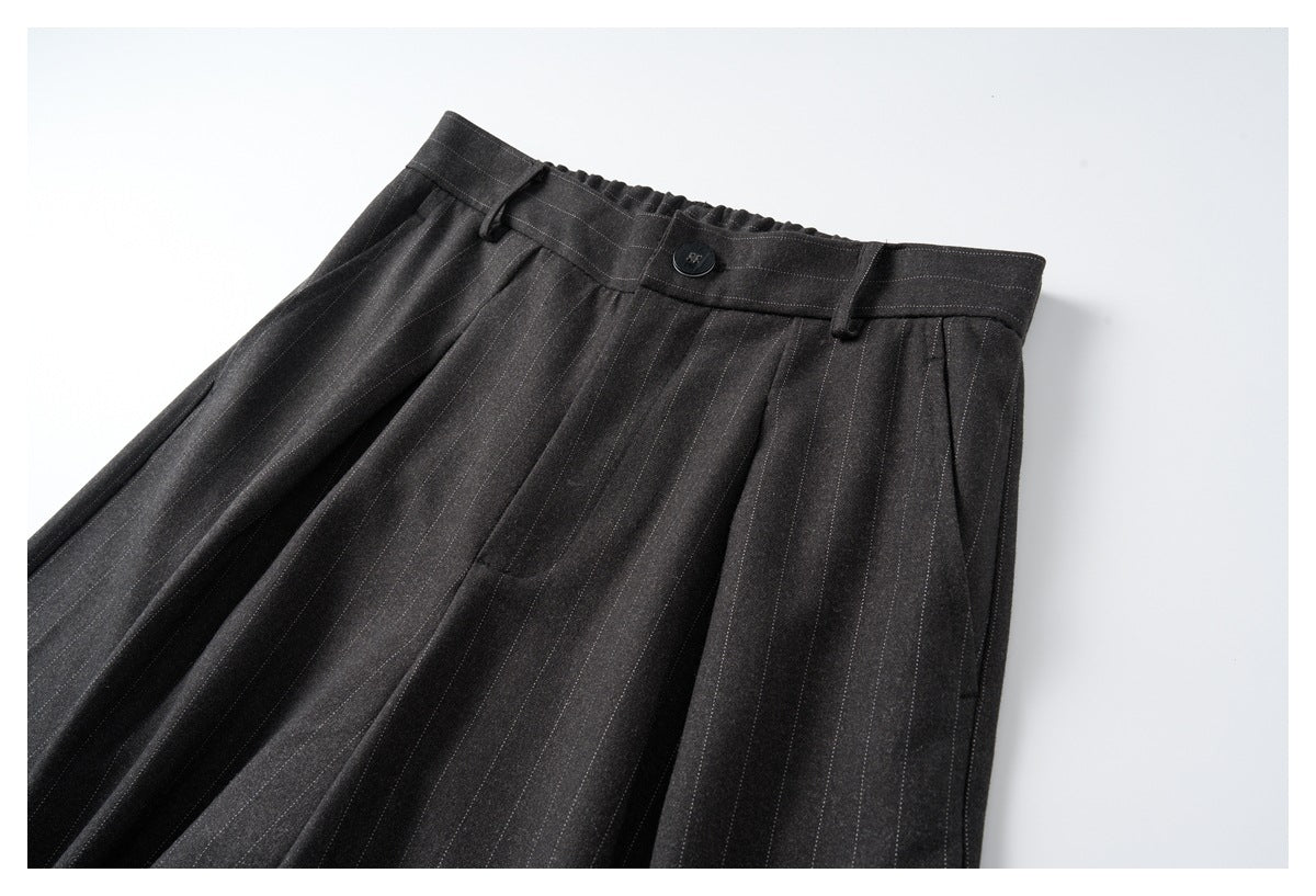 Angled front view of charcoal pinstripe trousers, cropped to show the pleated waistband, button and side pockets.