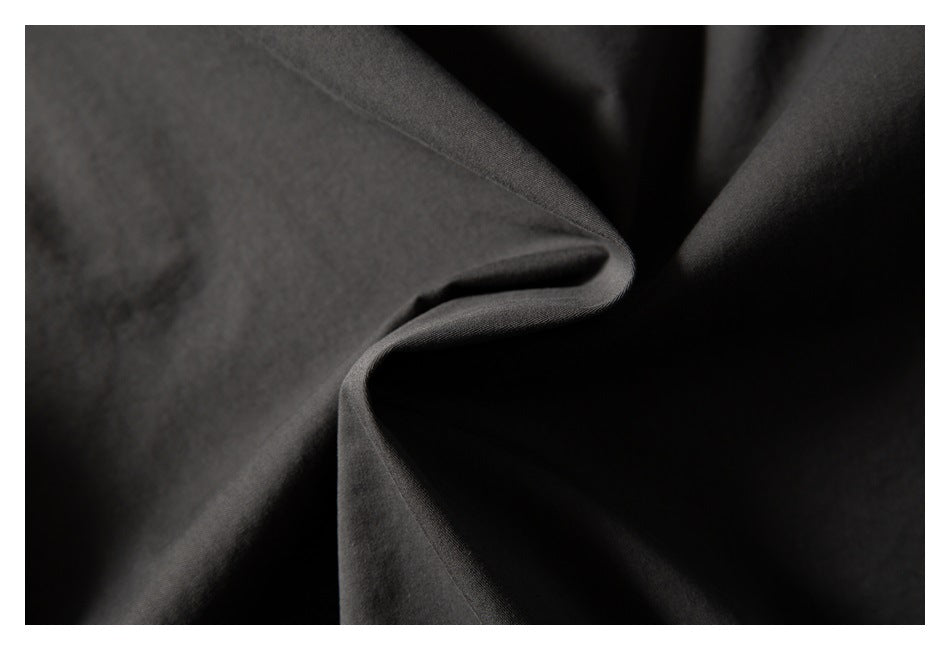 Close-up of smooth charcoal fabric arranged in soft folds.