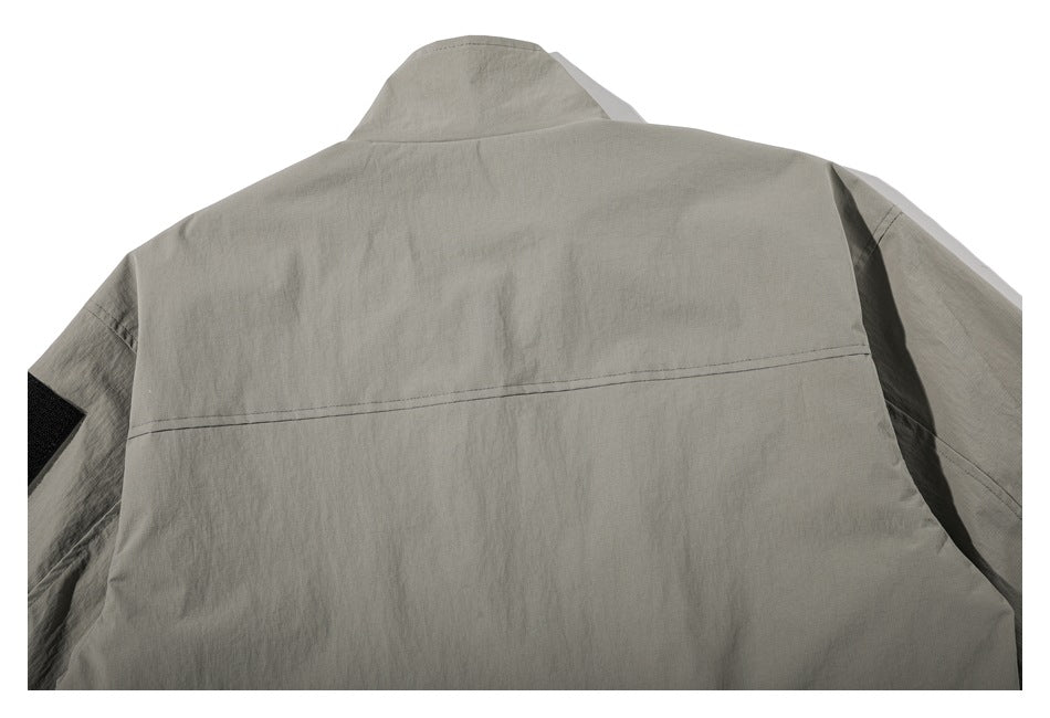 Close-up rear view of a light gray jacket showing its raised collar, shoulder yoke seam, and sleeves.