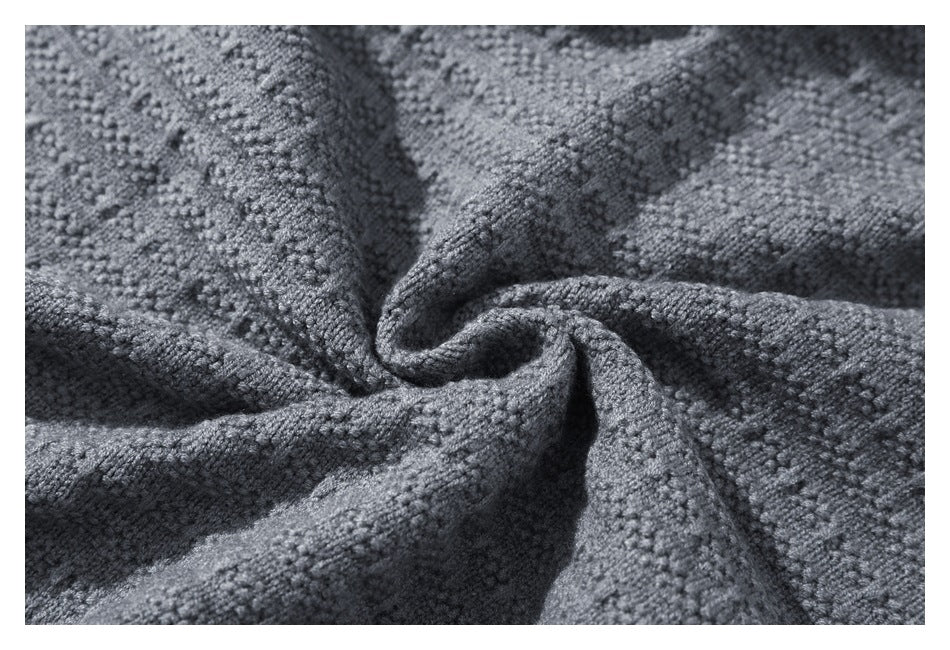 Close-up of gray knitted fabric gathered into folds, showing its textured weave.