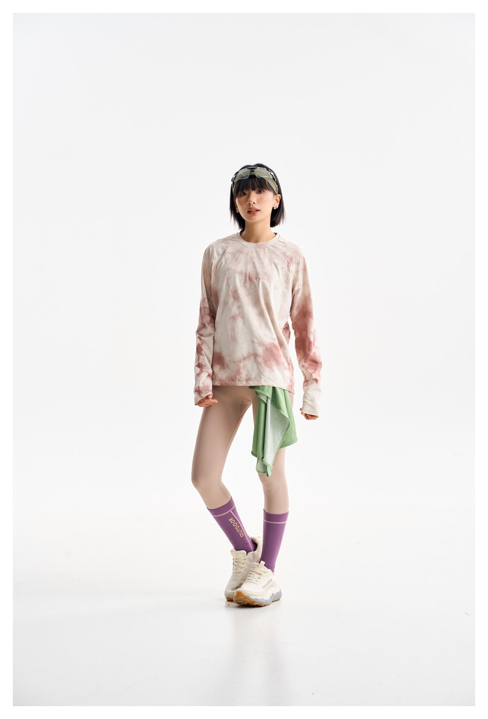 Model wearing a cream and dusty pink tie-dye long-sleeve top with beige leggings and purple socks, facing forward.