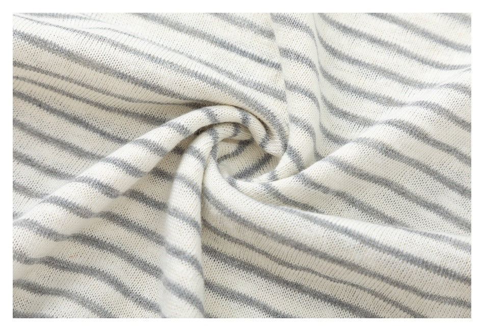 Close-up of softly twisted off-white knit fabric with narrow gray stripes.