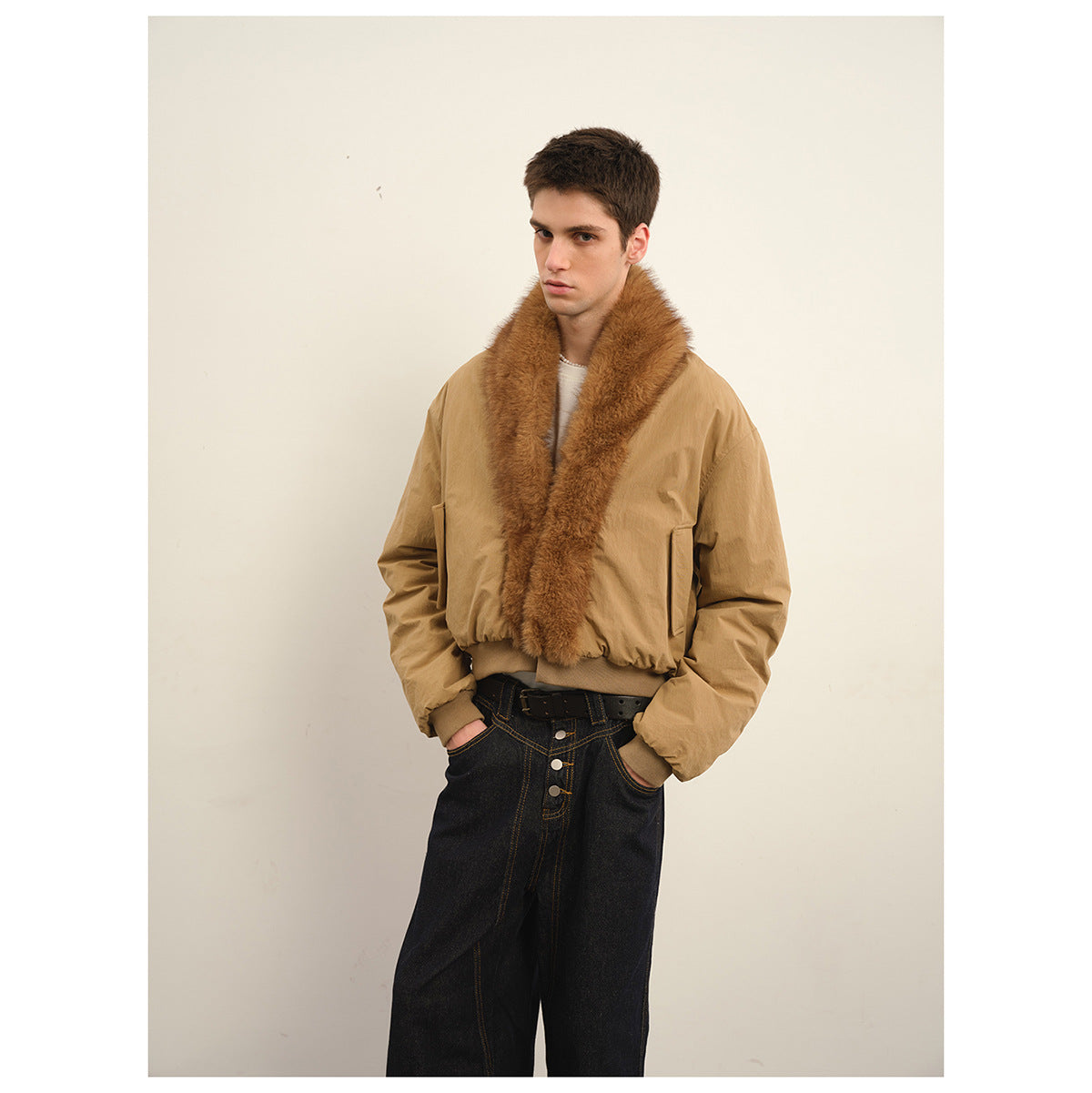 Model wearing a tan bomber jacket with a wide brown plush collar and black wide-leg jeans, shown from the front.