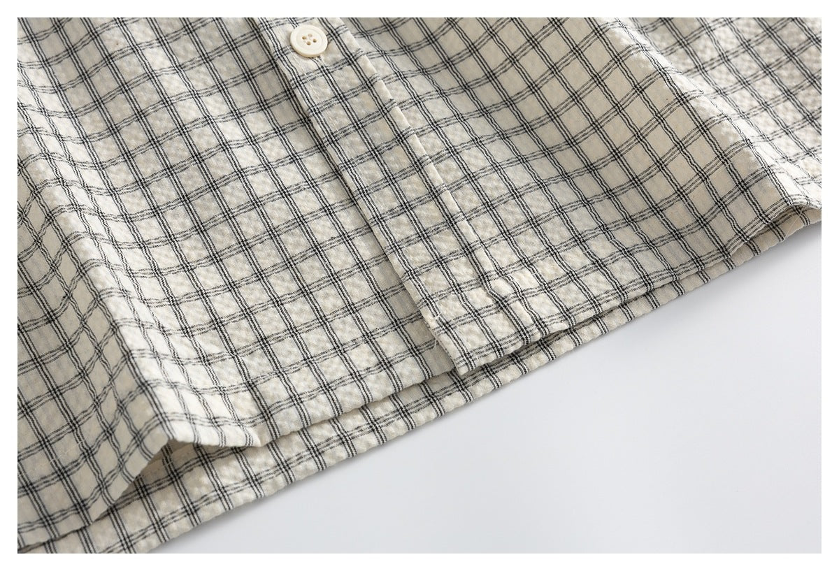 Close-up of the hem and lower front of an ivory shirt with a fine black plaid pattern.