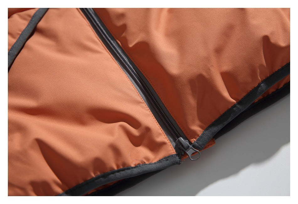 Close-up of the rust-orange jacket's dark front zipper and black-trimmed hem.