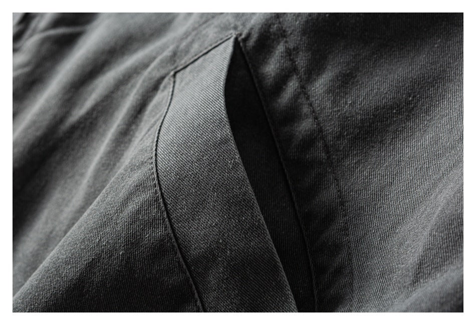 Close-up of dark gray twill garment fabric with a curved stitched seam and folded edge.