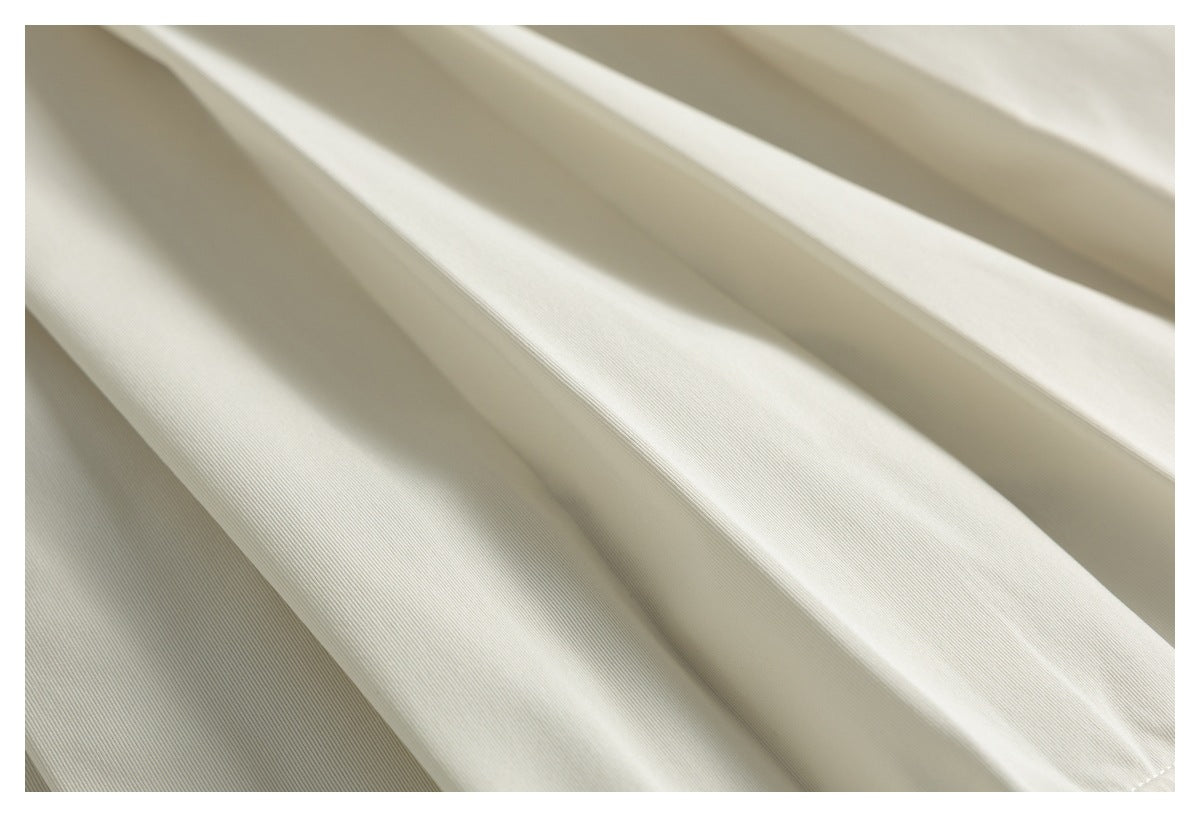 Extreme close-up of the smooth cream fabric arranged in broad folds.