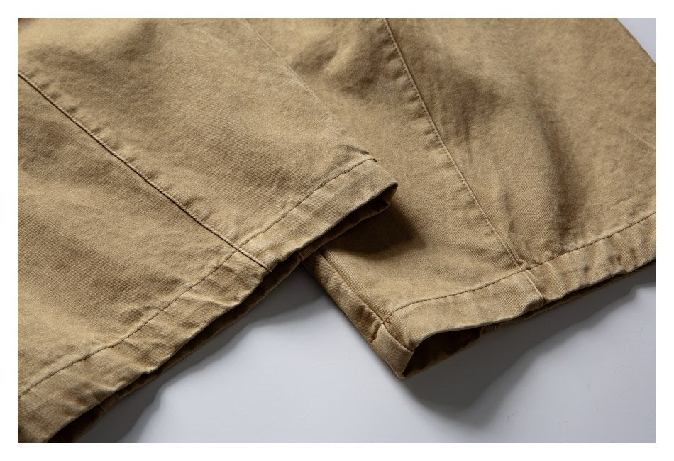 Close-up of the tan shorts' stitched leg hems and overlapping fabric.