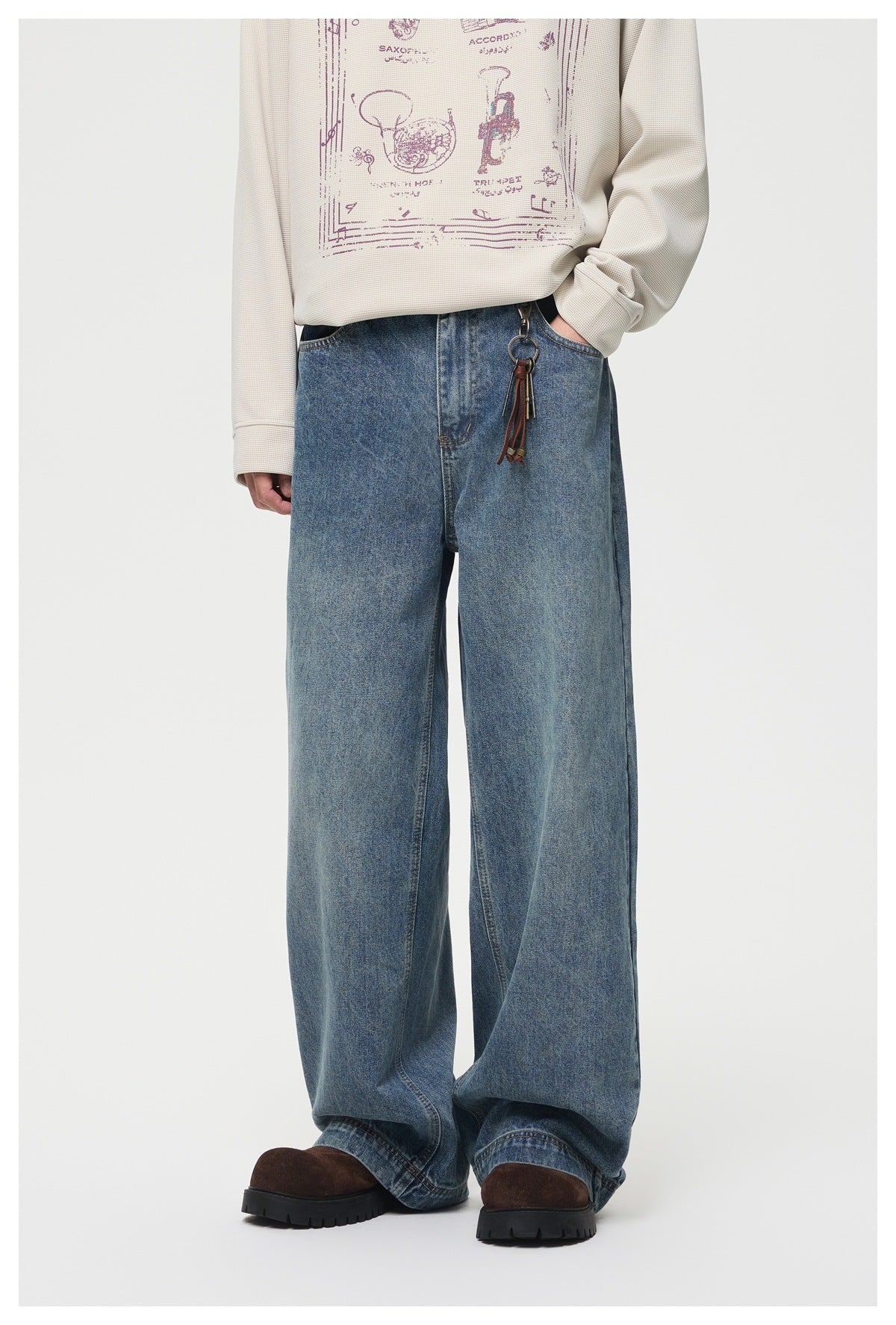 Model wearing washed blue wide-leg jeans with a cream long-sleeve top, key charm and brown chunky shoes