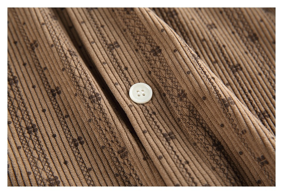 Close-up of a white button and dark patterned stripes on the tan shirt's ribbed fabric.