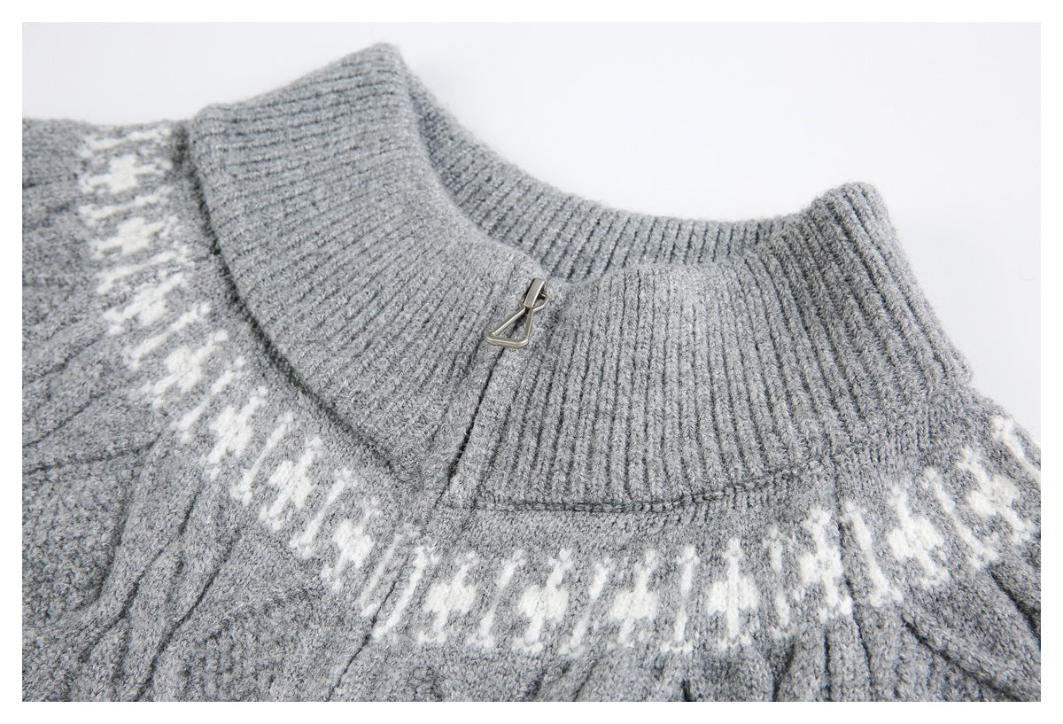 Close-up of a light gray sweater's ribbed high collar, small metal fastener, and white patterned yoke.