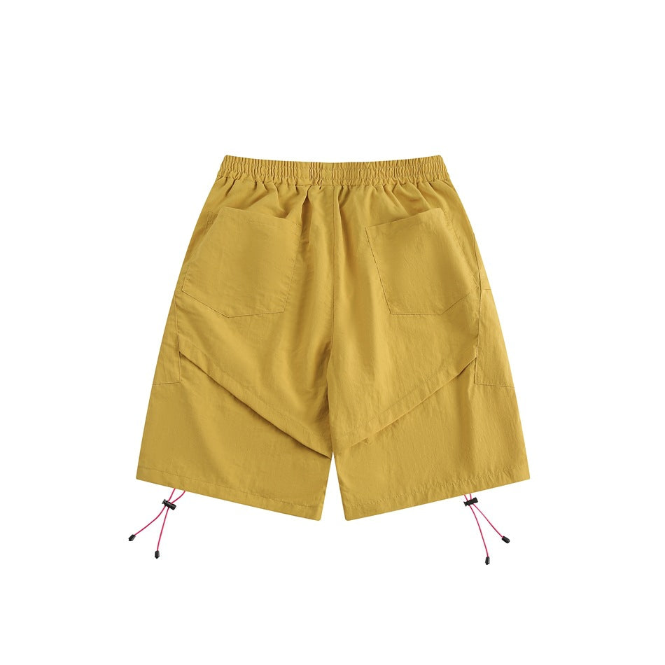 Yellow knee-length shorts, back view, with two patch pockets, an elastic waistband and pink hem drawcords