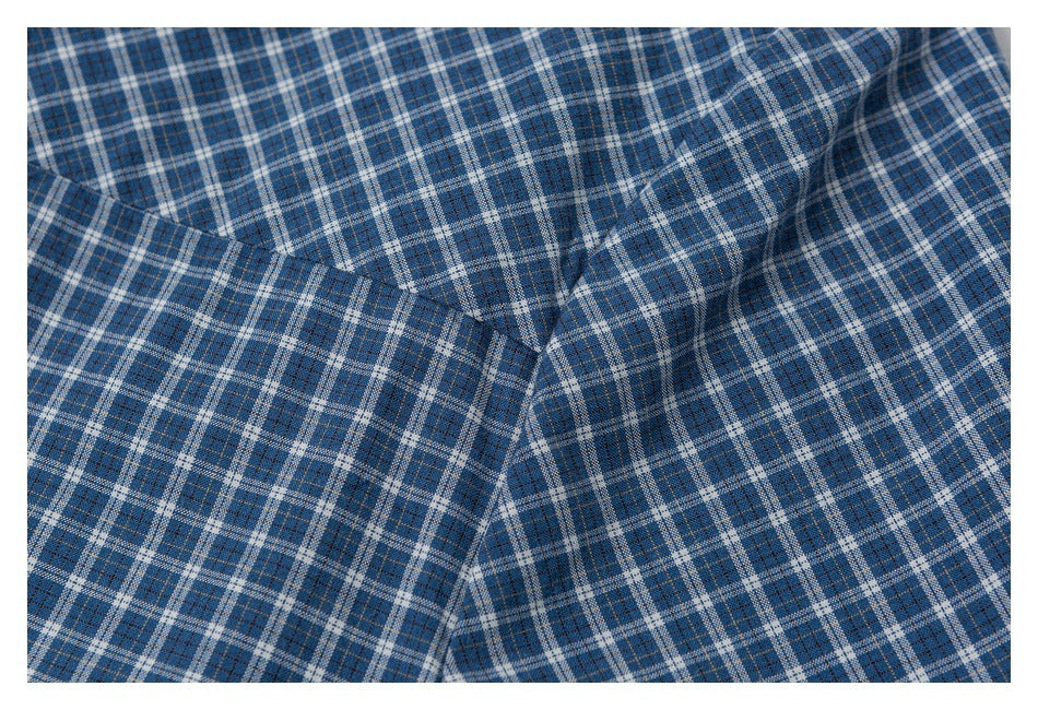 Close-up of blue plaid shirt fabric gathered around a seam and folded panel.