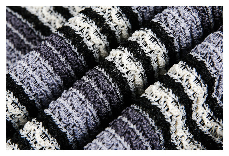 Close-up of chunky open-knit fabric with irregular black, gray, and off-white stripes.