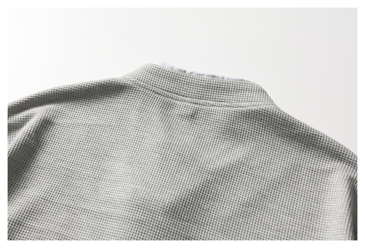 Close-up of the upper back and neckline seam of a light gray waffle-textured top.