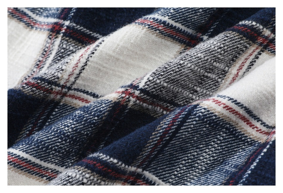 Macro view of the textured navy, white, gray, and red plaid shirt fabric.