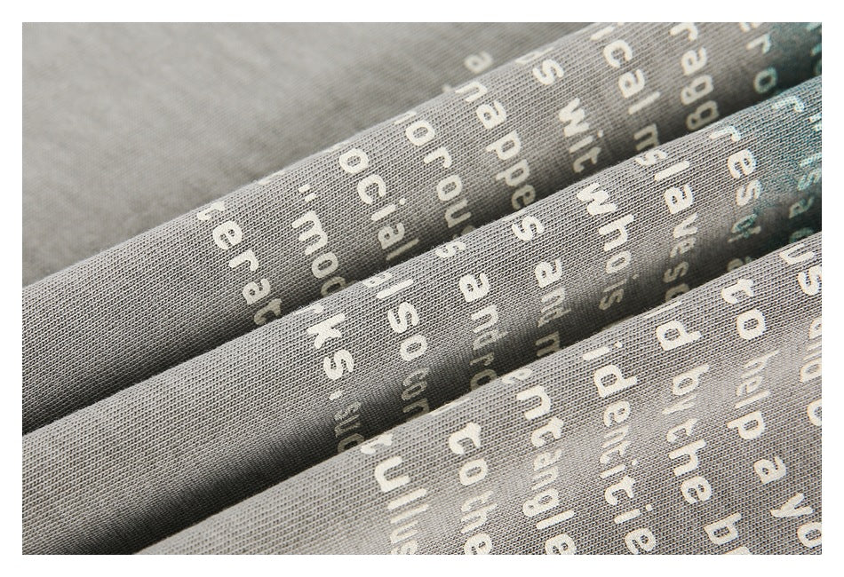 Folded gray fabric showing a close-up of white and teal English text print.