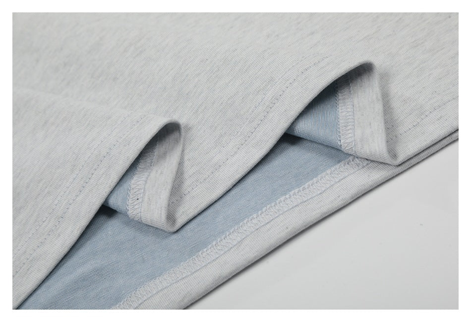 Close-up of a light gray T-shirt hem turned back to show the inner seam and pale blue-gray underside.