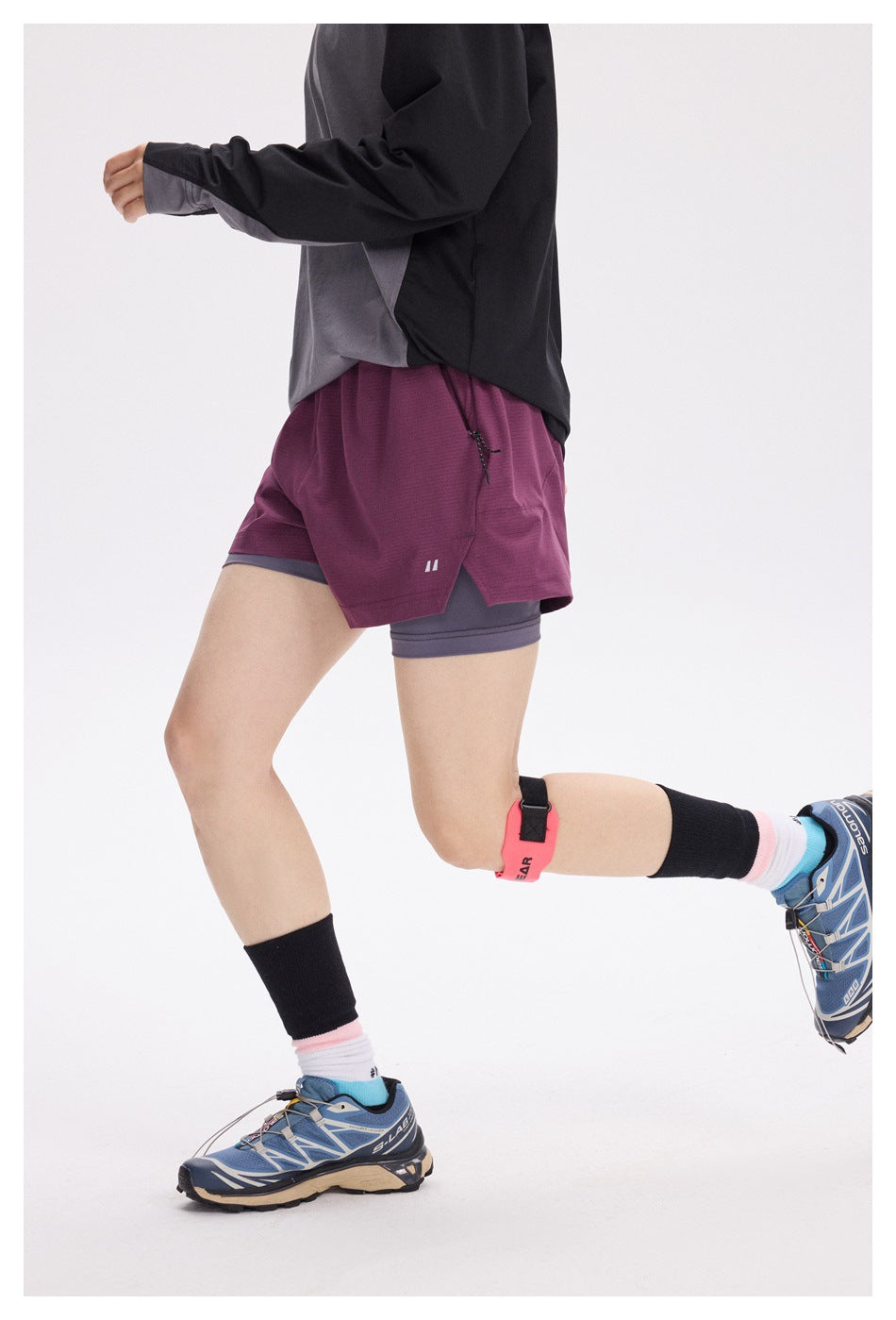 Side and rear view of a model running in burgundy shorts layered over gray compression shorts.