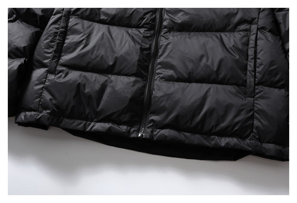 Close-up of the lower front of a black quilted jacket, showing the zipper and vertical pocket openings.