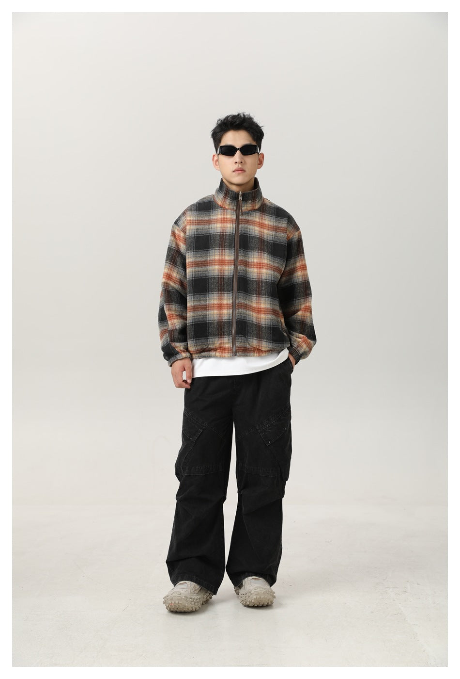Front view of a man wearing a black, gray, and rust plaid zip jacket with a stand collar.