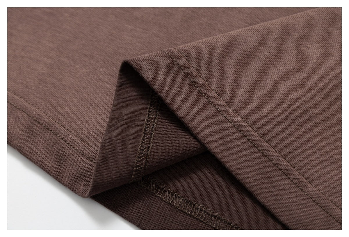 Close-up of a brown garment hem folded to show the stitching and overlocked seam.